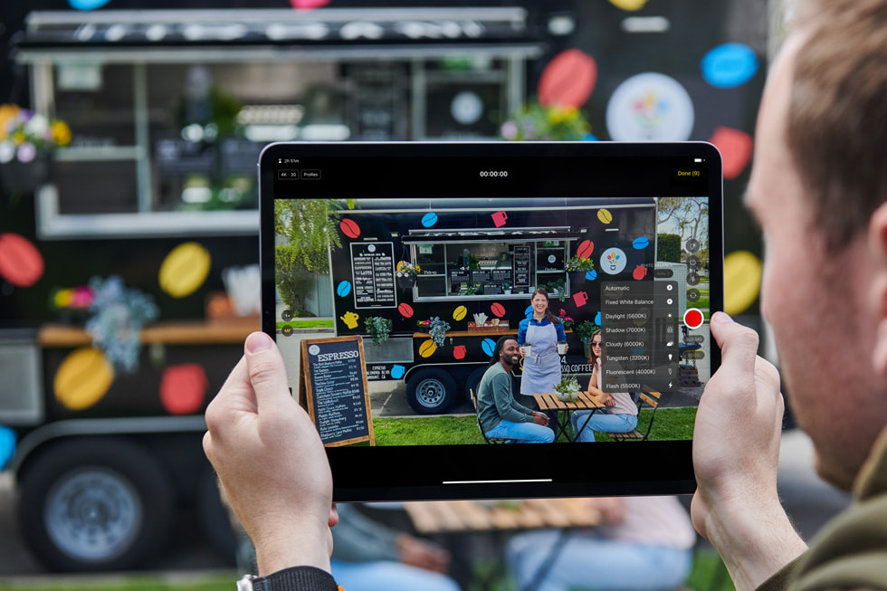 En person använder Final Cut Pro på iPad utomhus framför en foodtruck som serverar espresso.