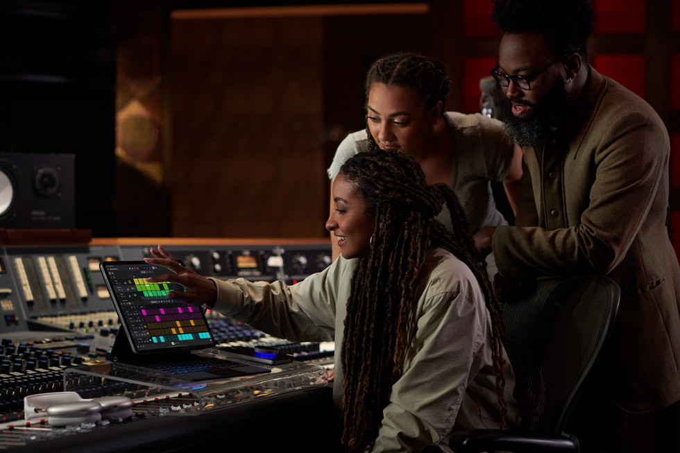 Three people huddle in a studio using Logic Pro for iPad.