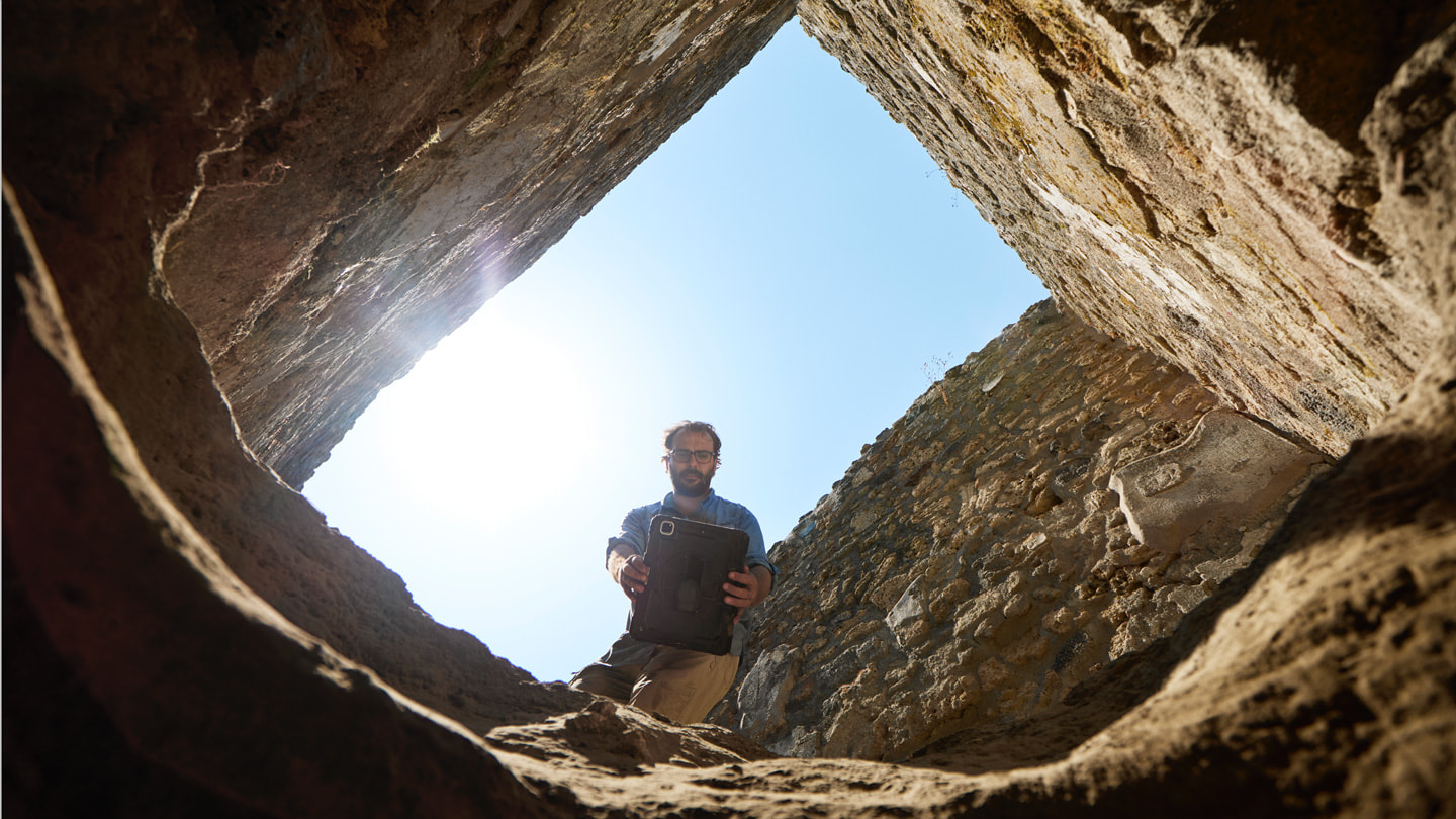 Ritratto dall’interno di uno scavo, il dottor Rogers è visto dal basso e tiene in mano un iPad Pro sopra l’apertura dello scavo.