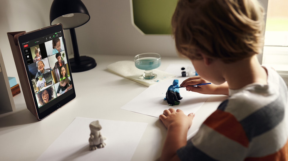 A child using the new iPad while painting a figurine. 