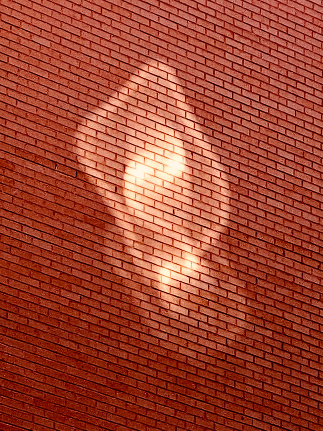 Une photographie d'un mur de briques avec des reflets lumineux prise avec un iPhone 11 Pro Max par Axel Morin à Paris, en France.