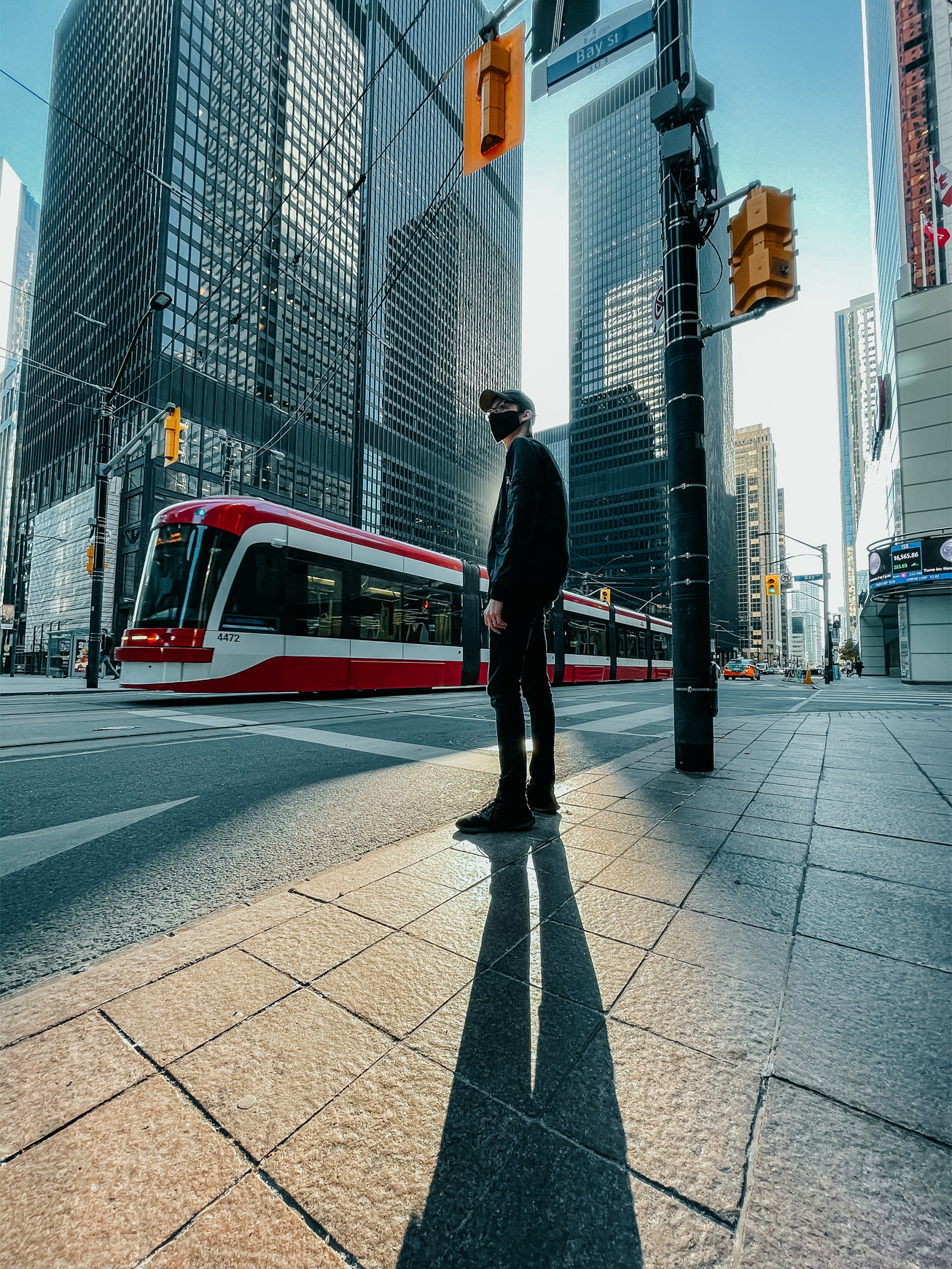 A person casts a long shadow on a city street.