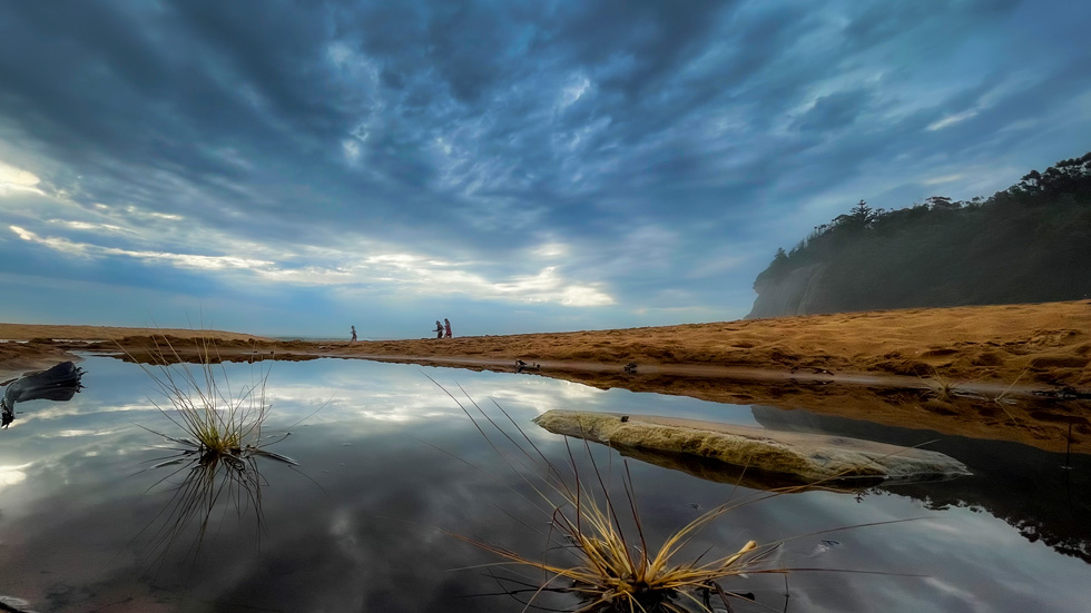 A body of water mirrors the expanse of sky above.