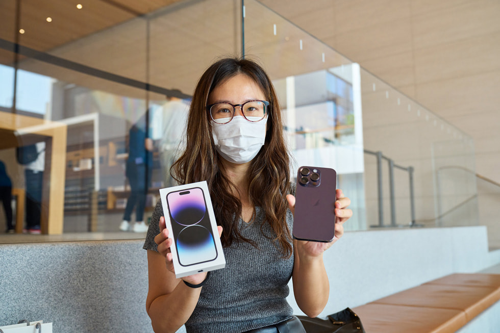 En Apple Sanlitun-kund poserar med sin nya iPhone 14 Pro i djuplila.