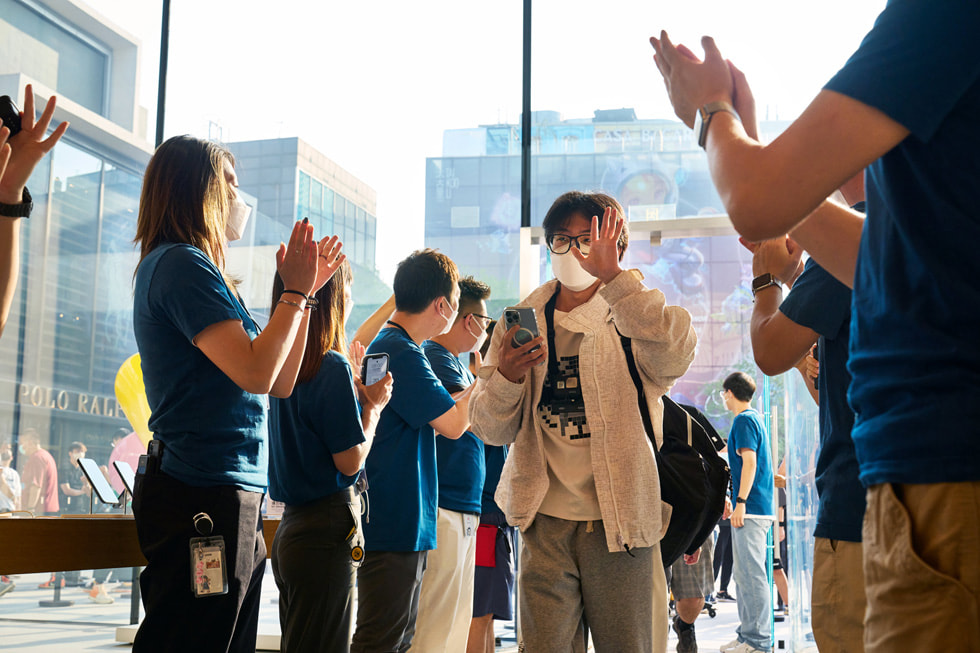 Apple Sanlitun-medarbetare klappar händerna medan en kund går in i butiken.