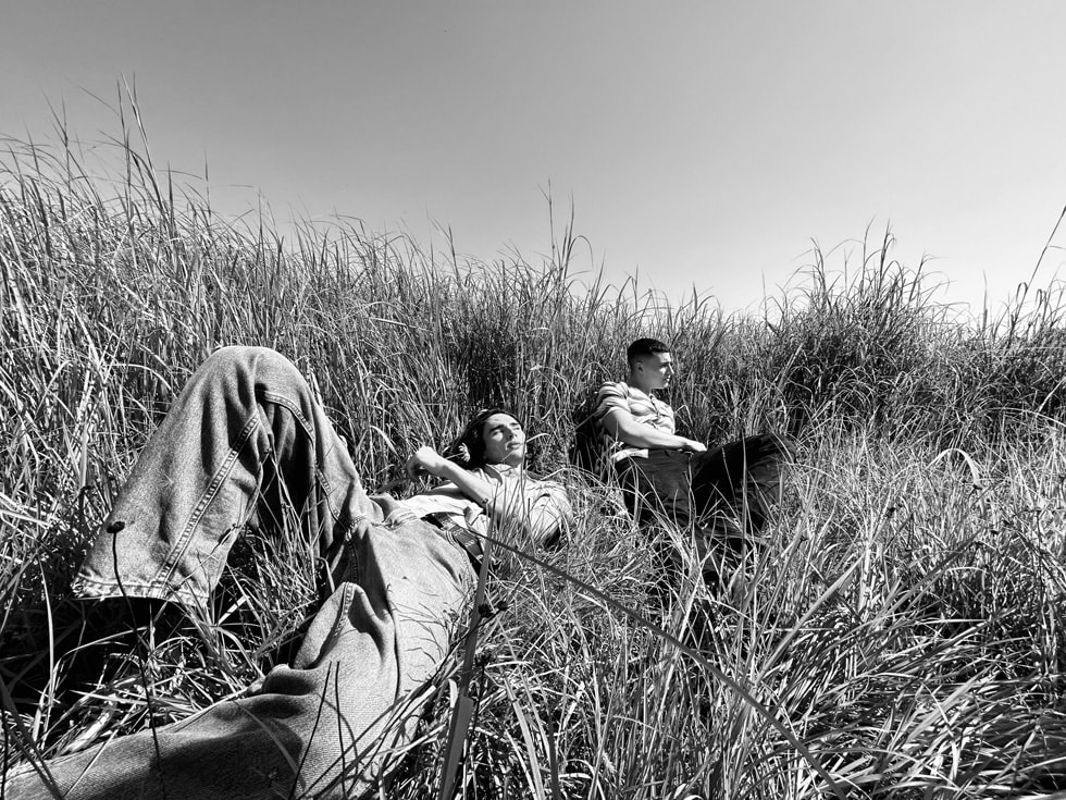 Two people recline in a black-and-white photo taken in a field.