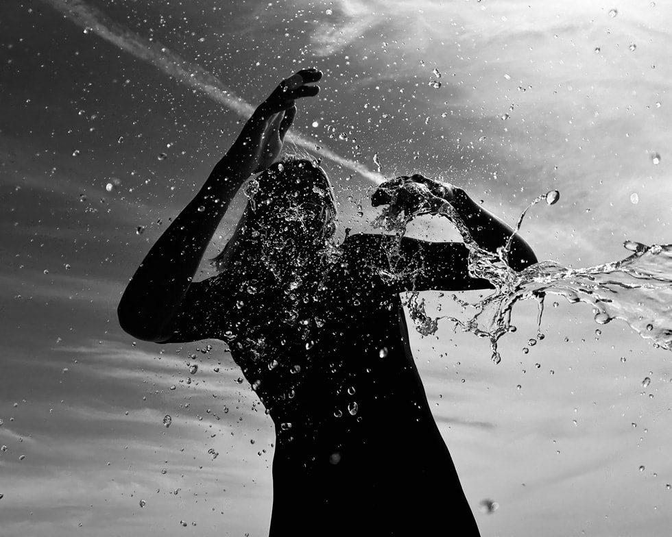 Svartvit bild tagen på iPhone av vattendroppar som faller från en person i silhuett.
