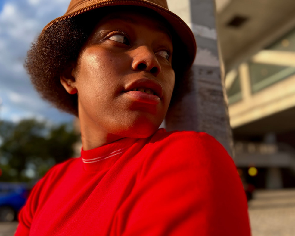 A person in a red shirt leans against a post in this image captured on iPhone.