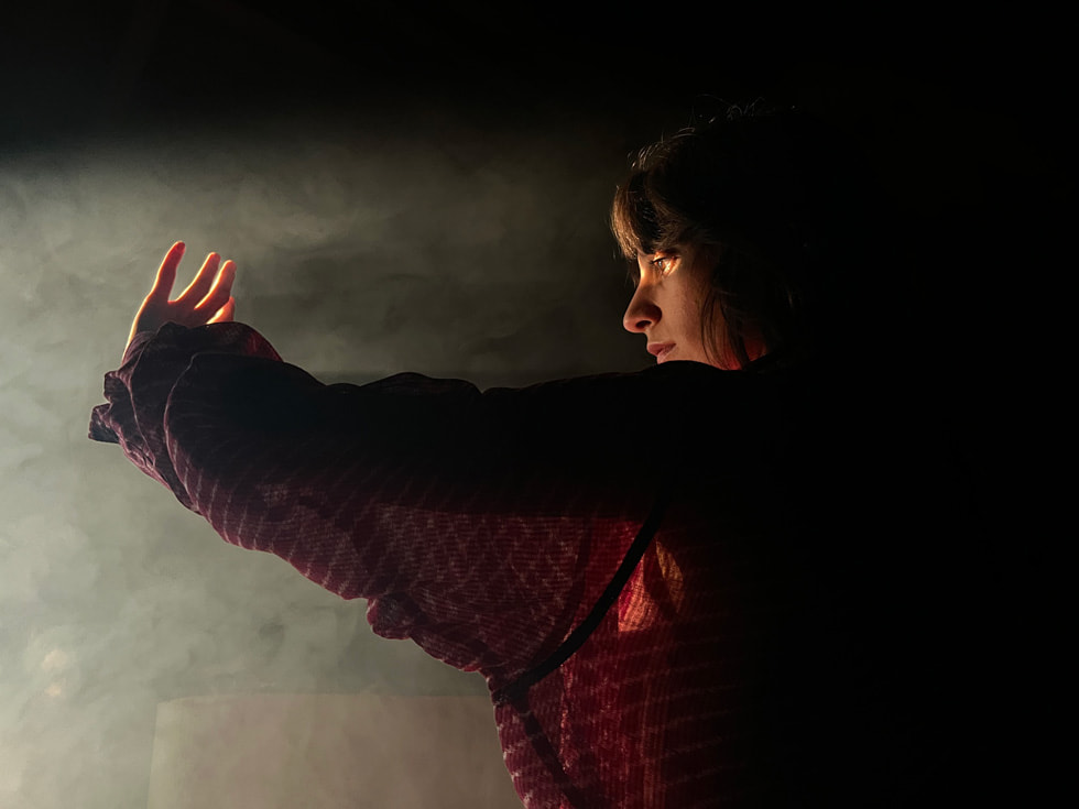 Фотография женщины в полумраке, сделанная на широкоугольную камеру iPhone 13 Pro.