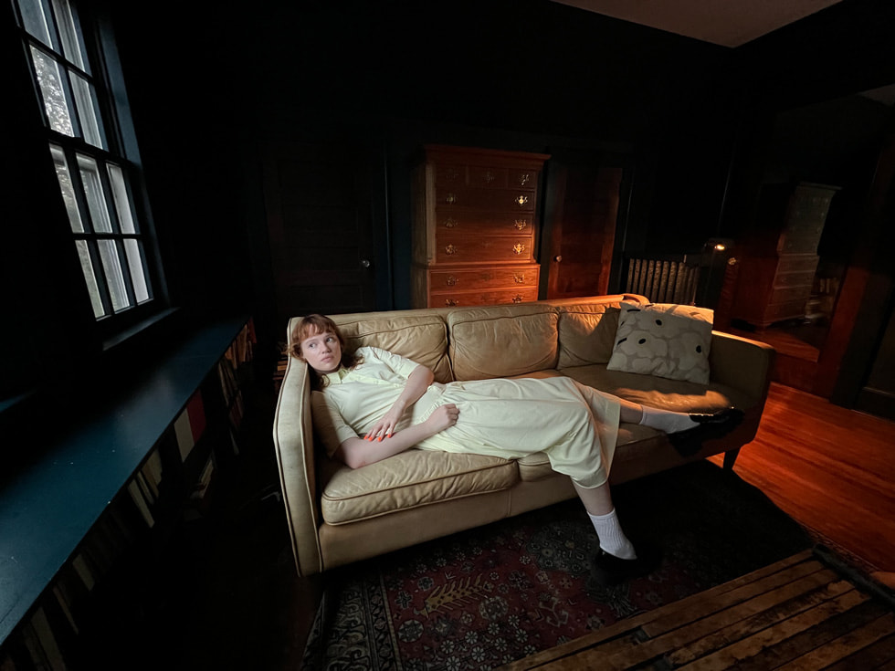 Фотография женщины на диване, снятая на сверхширокоугольную камеру iPhone 13 Pro.