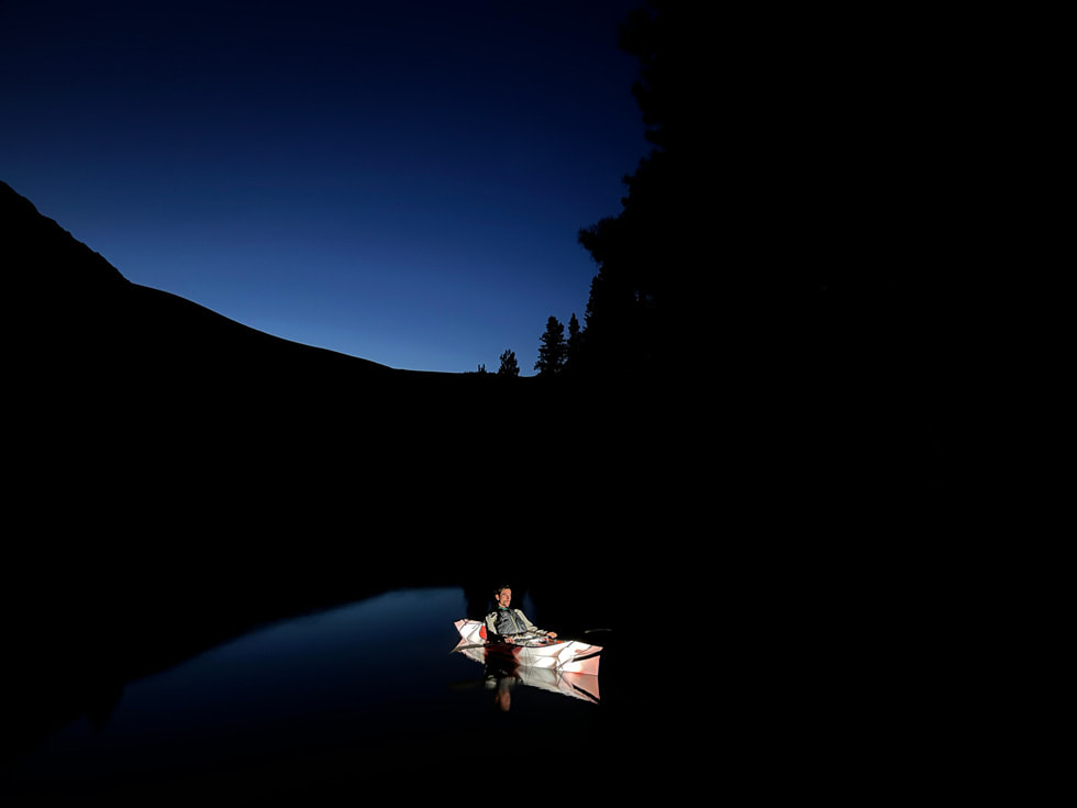 Foto nocturna de un hombre en una canoa hecha con el gran angular del iPhone 13 en modo Noche.