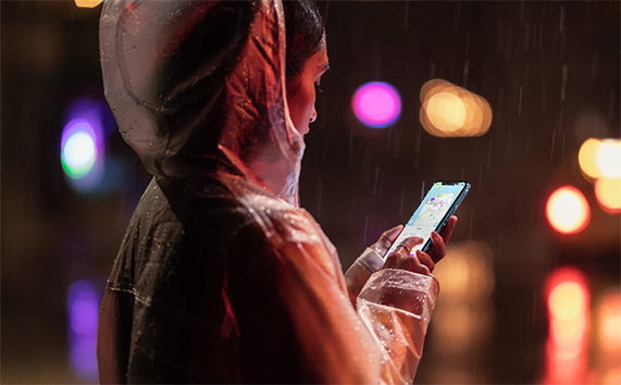 빗 속에서 iPhone XR을 들고 있는 여성.