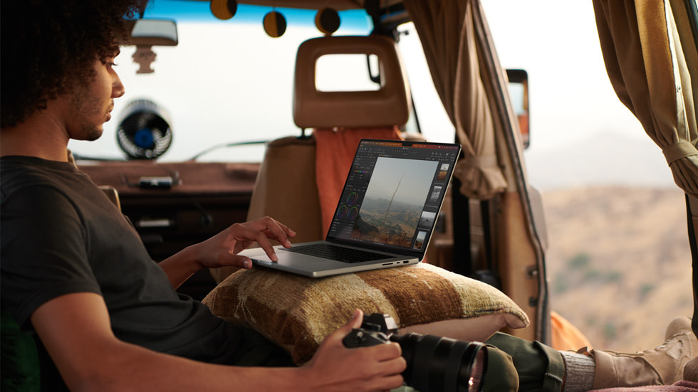 A photographer using MacBook Pro with M2 Max inside a van.