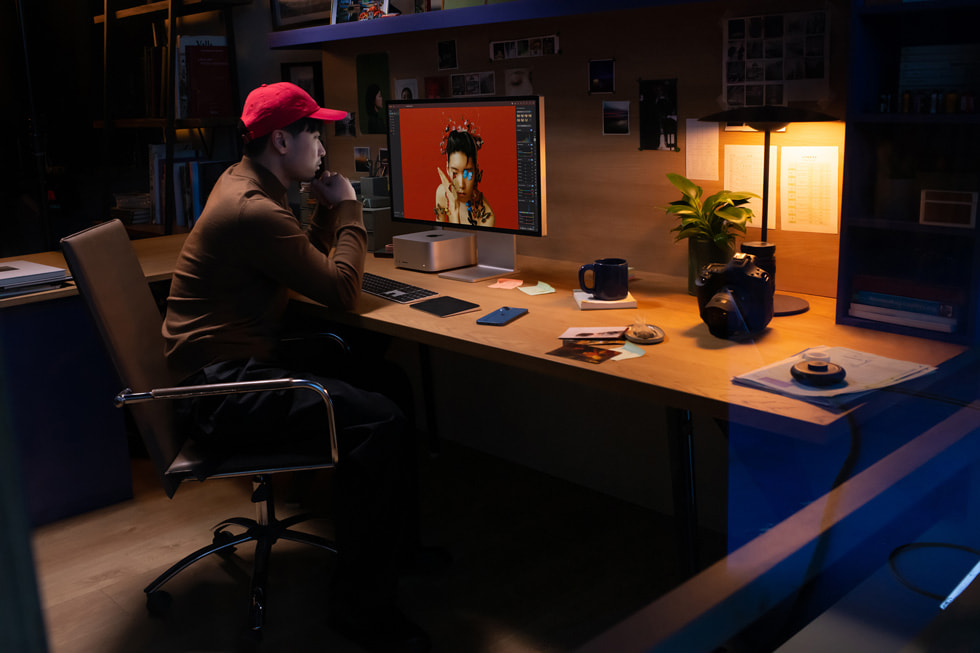 En kreativ fagperson arbejder med Mac Studio og Studio Display i et kontormiljø.