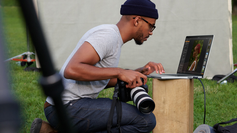 A photographer uses MacBook Pro to edit photos on location outdoors.