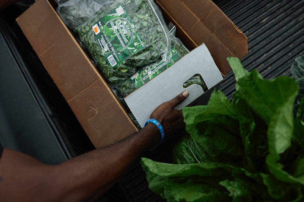 Alguien sostiene una caja con productos de una cooperativa agrícola.