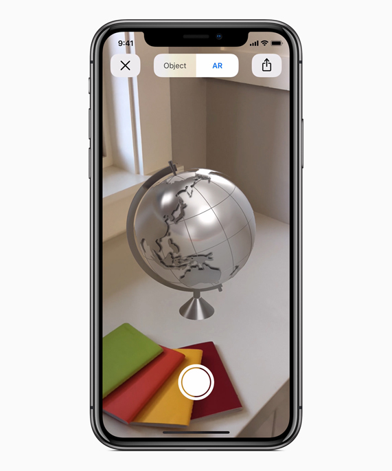 iPhone X affichant un globe en RA sur un bureau.