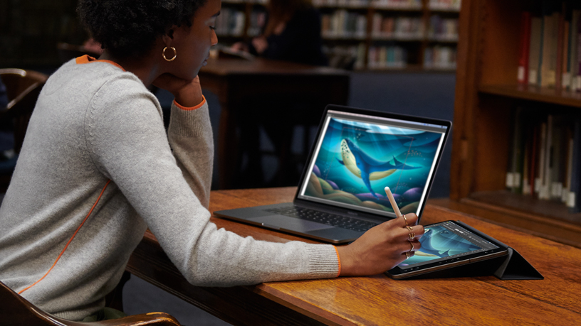 Utente MacBook che espande il workspace con iPad e Apple Pencil.