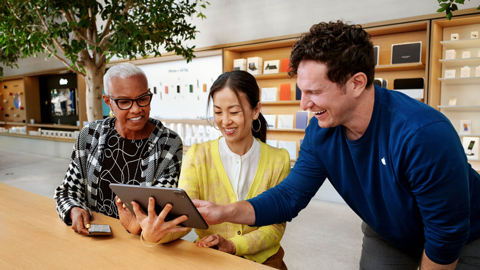 Ein Apple Specialist, der Kund:innen in einem Apple Store an einem iPad Pro bedient.
