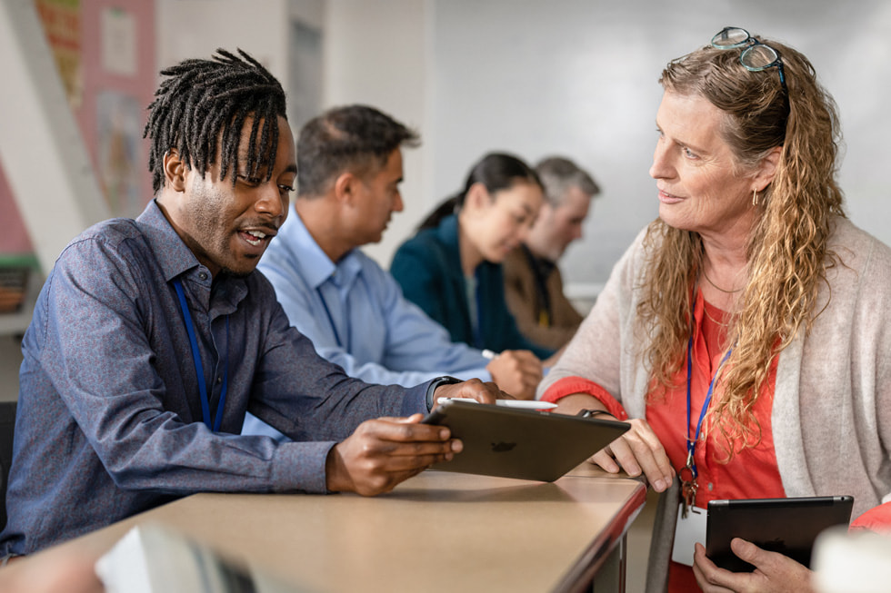 An Apple Learning Coach educator coaching a teacher on iPad.