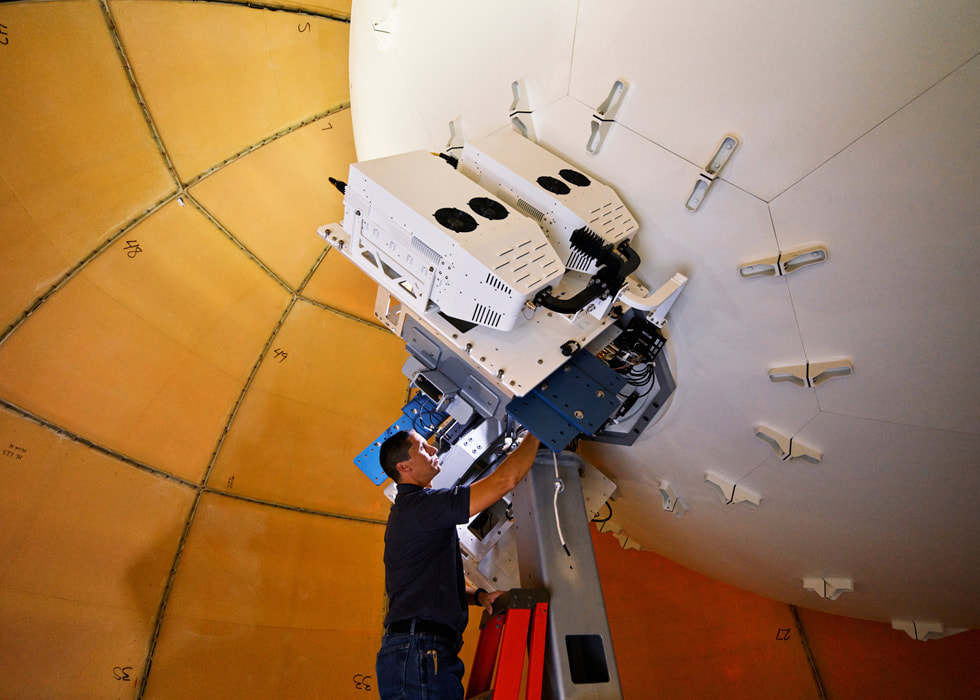 A satellite technician stands on a ladder.