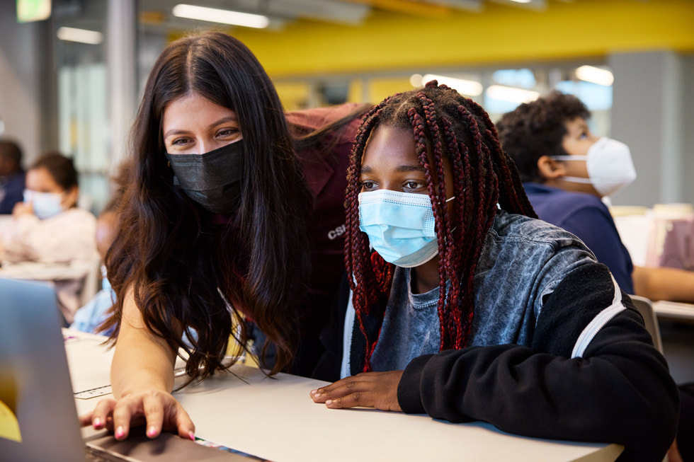 An instructor and a student collaborate in a classroom environment.