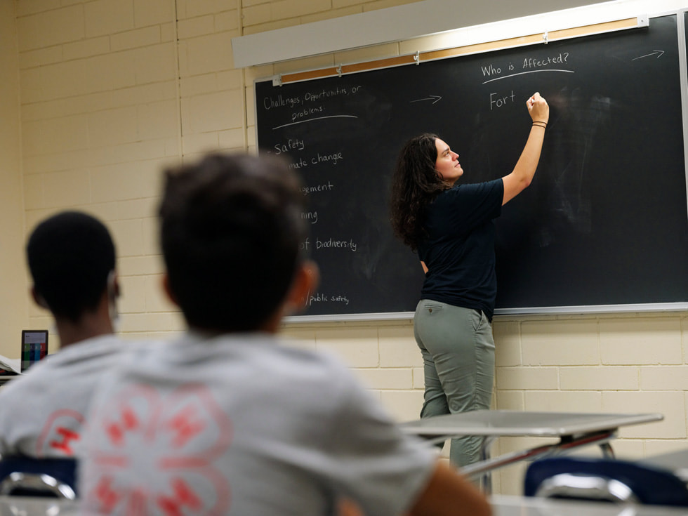Eine Lehrkraft des Rutgers 4-H Computers Pathways Program schreibt auf eine Tafel.
