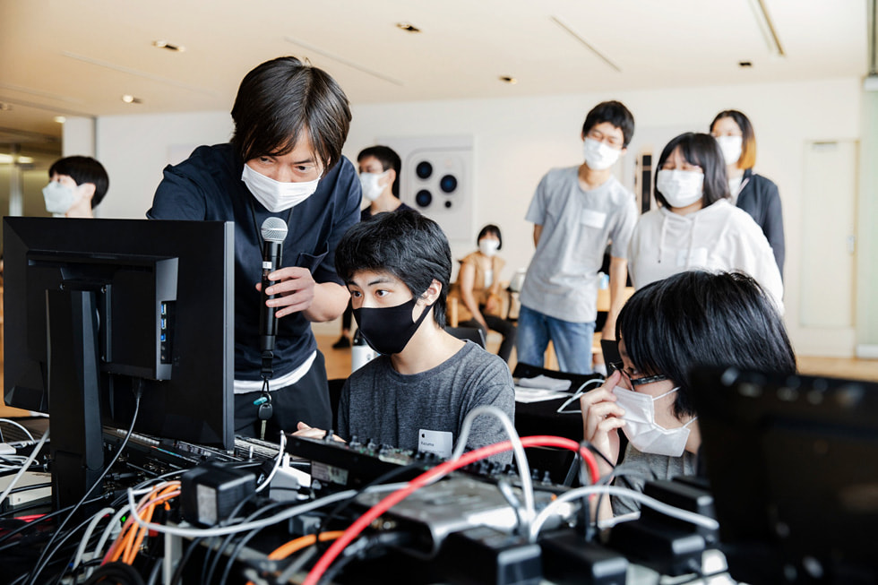 Ein:e Apple Freiwillige:r mit einem Mikrofon beim Creative Studios Programm in Tokio mit Mitgliedern von Sankakusha.
