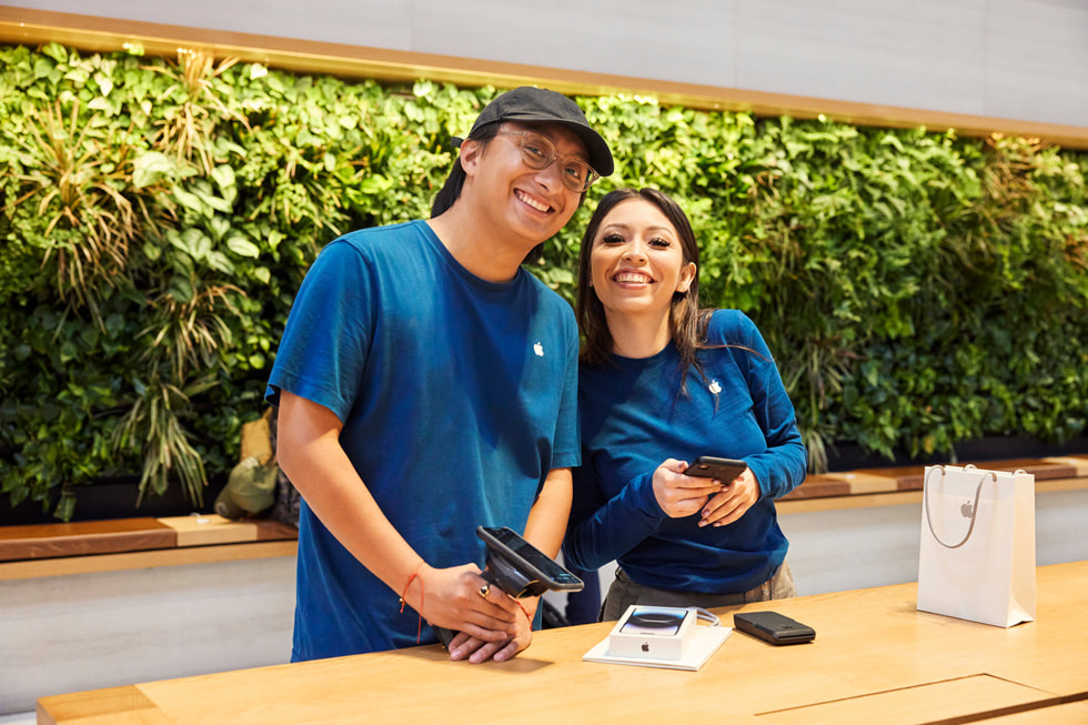 Dos Especialistas de Apple sonríen desde detrás de una mesa.