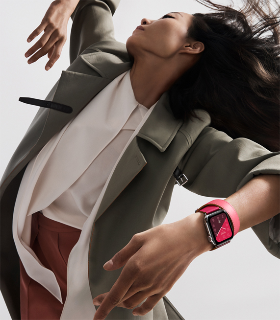 A woman wearing the new Apple Watch Hermès, in a bright colour-blocked band. 