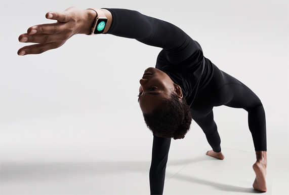 A woman performing a yoga pose on a mat, wearing Apple Watch Series 4 in gold.