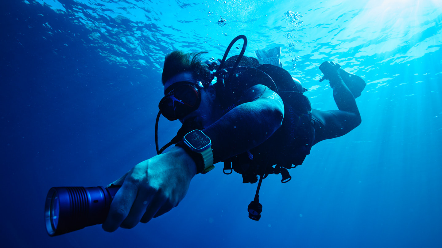 Oceanic+가 구동되는 Apple Watch Ultra를 착용한 스쿠버 다이버가 해수면 아래에서 수영하는 모습.