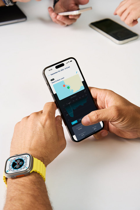 Andrea Silvestri ใส่ Apple Watch Ultra และมองที่แอป Oceanic+   บน iPhone สำหรับใช้งานควบคู่กัน