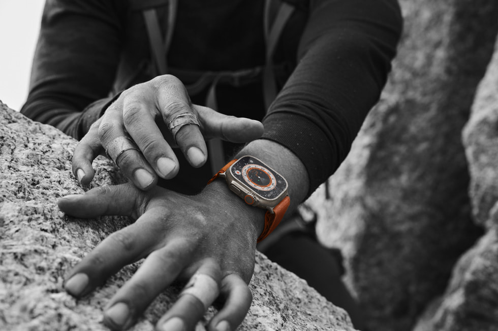 Nahaufnahme zweier bandagierter Hände auf einem Felsen und einer Apple Watch Ultra an einem Handgelenk.