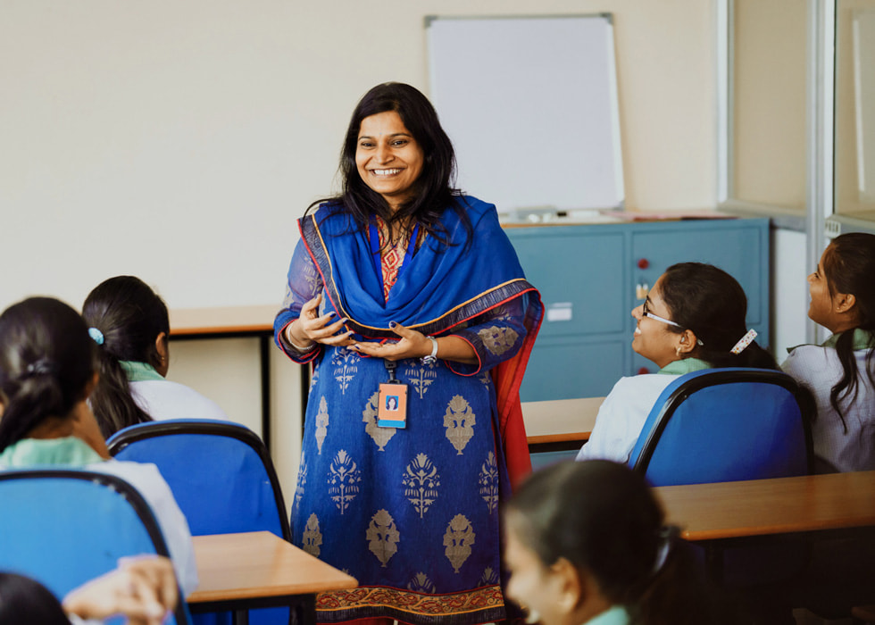 A woman instructs students in a classroom setting.