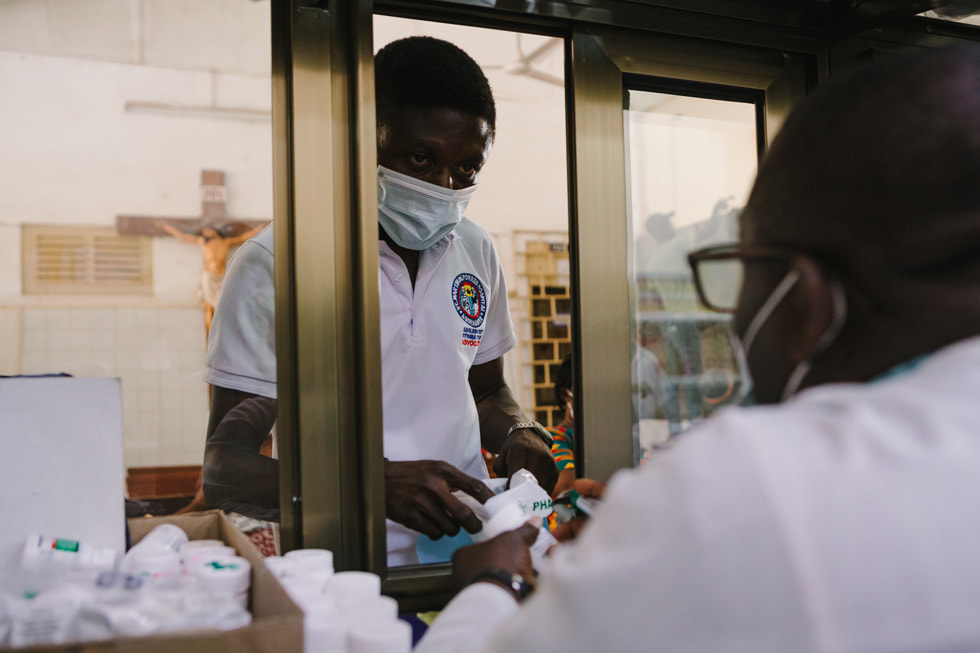 Model of Hope programme volunteer Joseph picking up antiretroviral therapy medications.