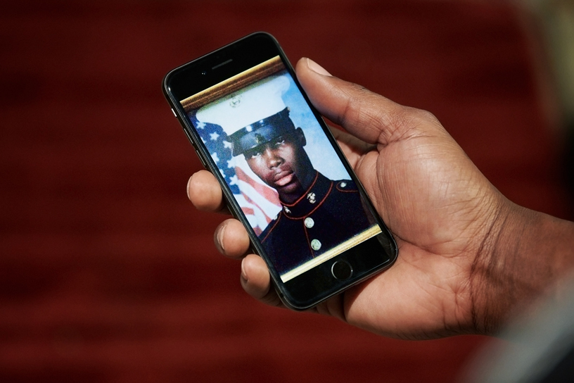 Gerald looking at a portrait of himself from the Marines on his iPhone.