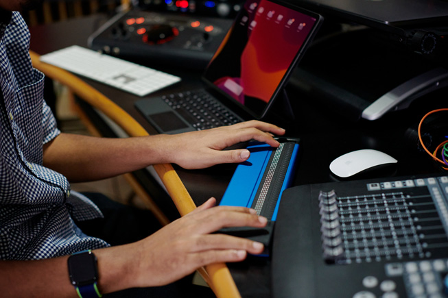 Primer plano de las manos de Matthew Whitaker usando un teclado braille para componer música.