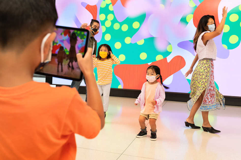 A child draws on iPad while participating in Apple Camp with their guardian.