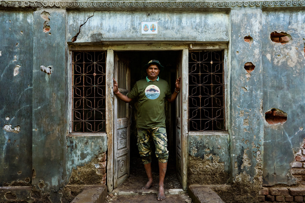 Mangesh Patil, pescatore, in piedi sulla soglia di un edificio nel villaggio di Ganesh Patti.