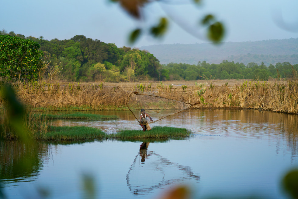 Een visser in Maharashtra waadt door het water.