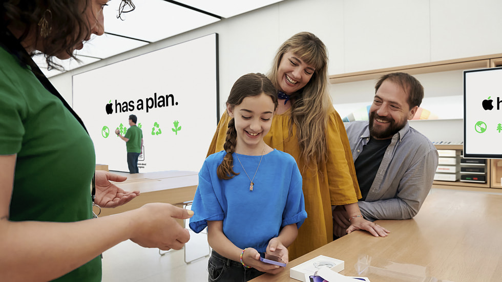 Twee volwassenen en een kind in gesprek met een medewerker van de Apple Store.