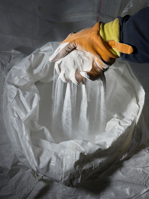 A worker sifts materials with a gloved hand.