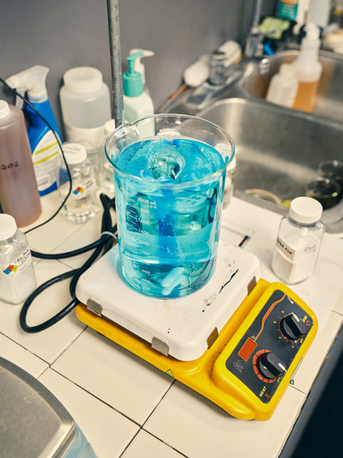 A blue chemical liquid being safely measured on a scale.
