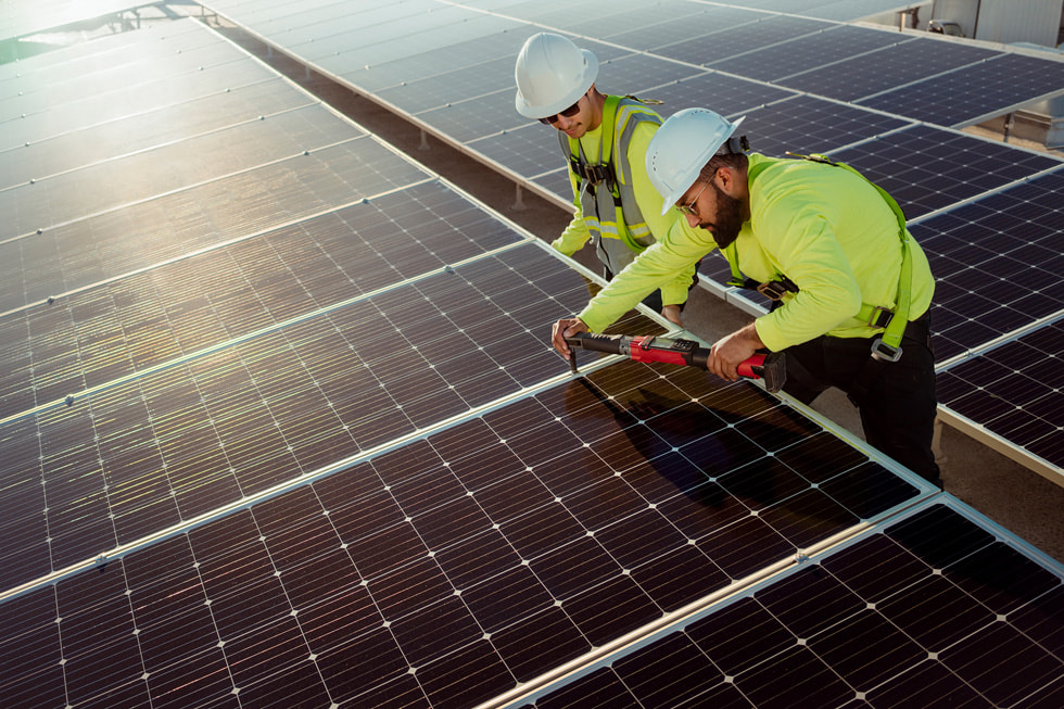 Duas pessoas com capacete de proteção em uma usina solar na Bench-Tek Solutions em Santa Clara, Califórnia.