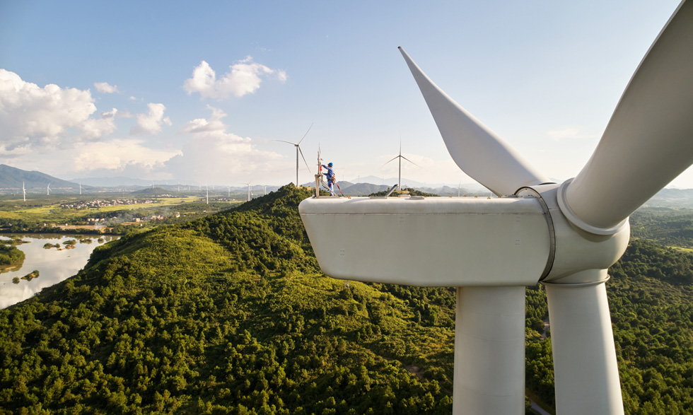 Personne effectuant des réparations sur une éolienne, à une centaine de mètres du sol.