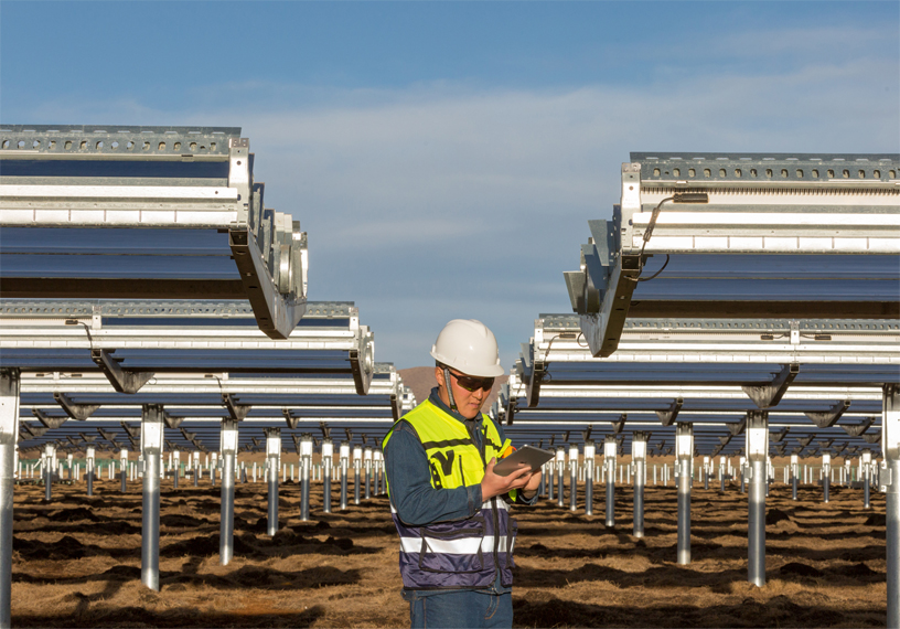 Travailleur se tenant devant des panneaux solaires dans une centrale photovoltaïque du Sichuan (Chine).