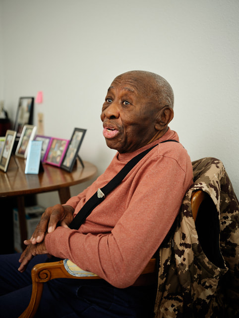 Veterans Square housing complex resident J.C. is shown seated in the building.