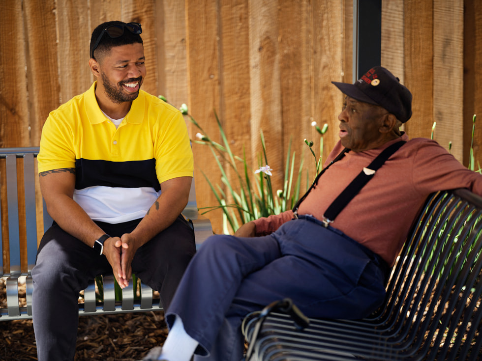 Veterans Square resident J.C. and building service coordinator Marcus Ferdinand converse on benches outside of the building.