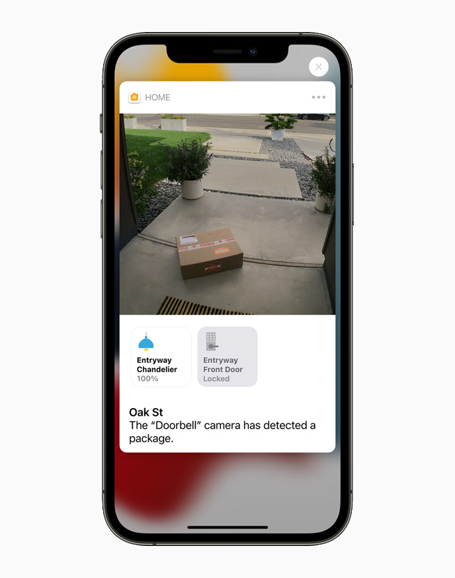 A HomeKit-enabled camera shows a package left near the front door, displayed on iPhone 12 Pro.